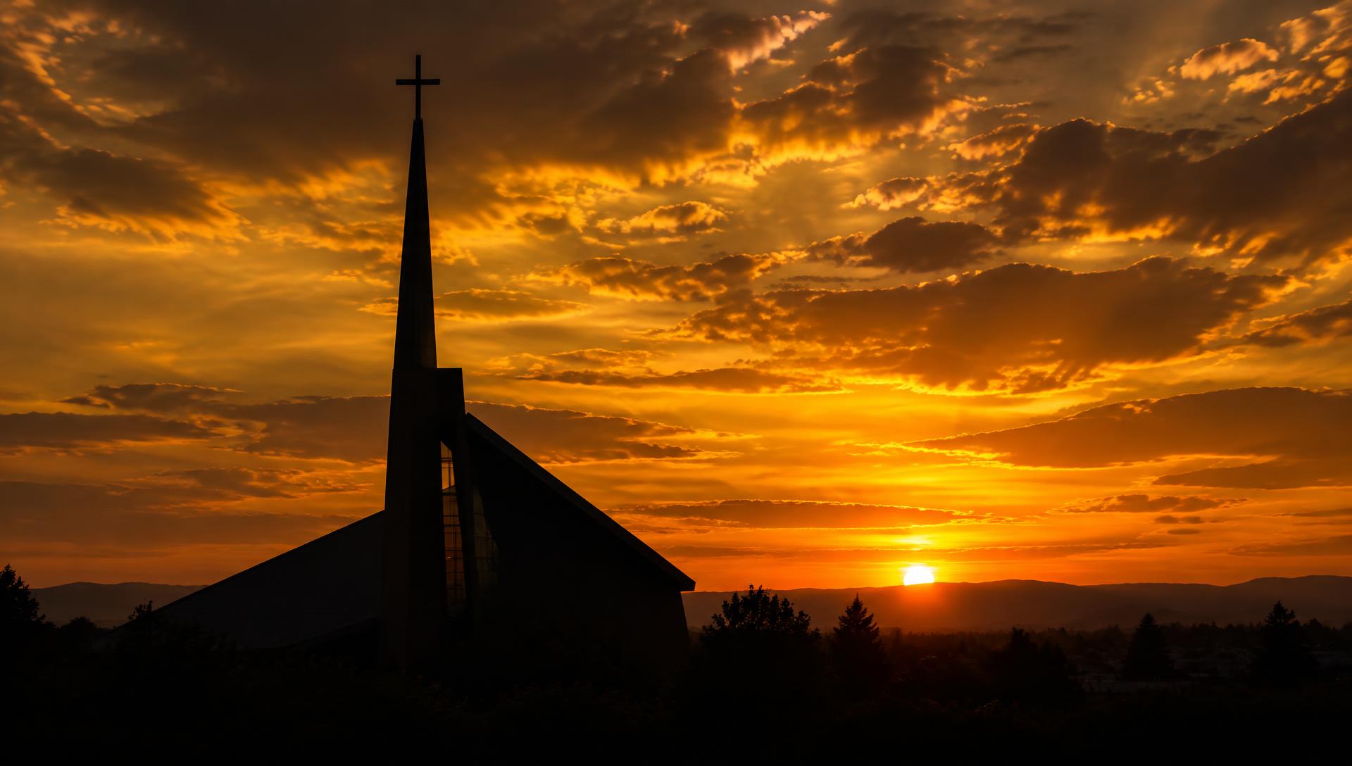 Church steeple silhouetted against a golden sunset